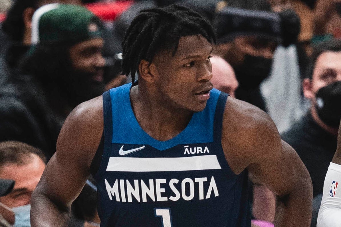 Anthony Edwards in a navy Minnesota Timberwolves number 1 jersey jogs up the court in front of courtside fans