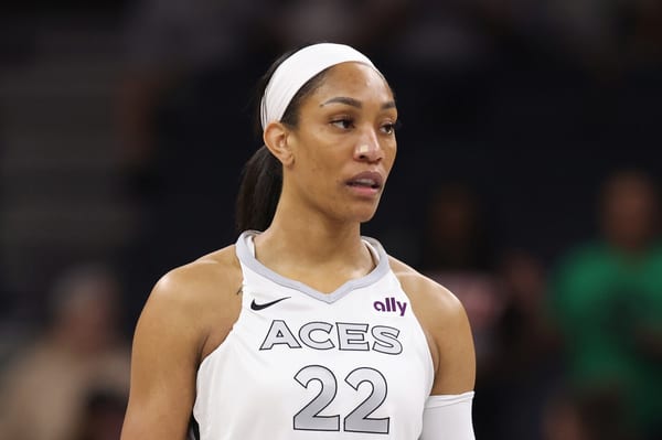 A'ja Wilson in a white Las Vegas Aces uniform, number 22, looking off to the side during a game