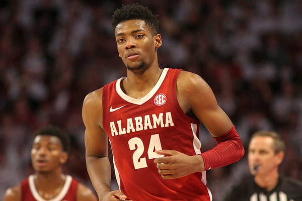 Brandon Miller in a red Alabama college jersey, number 24, jogs up the court during a game as a referee looks on