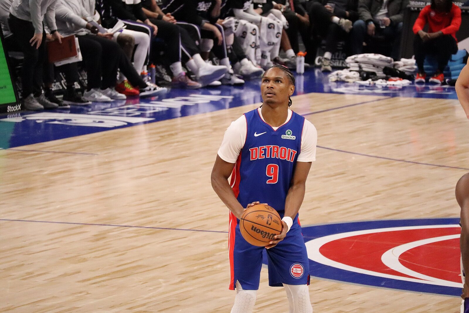Ausar Thompson in a blue Detroit Pistons jersey, number 9, holds the ball at the free-throw line and looks up at the rim