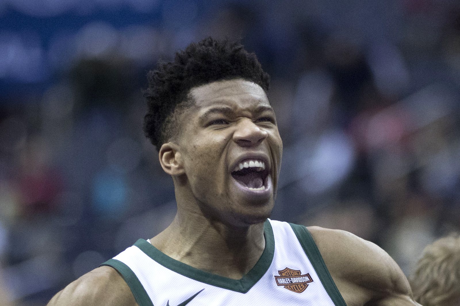 Giannis Antetokounmpo in a white Milwaukee Bucks jersey shouts with his mouth wide open before a game