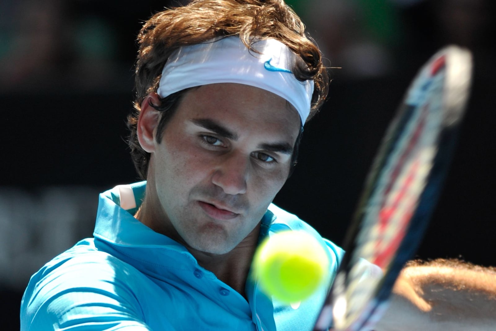 Roger Federer eyeing the ball on a backhand return, headband and racquet in frame, at the 2010 Australian Open